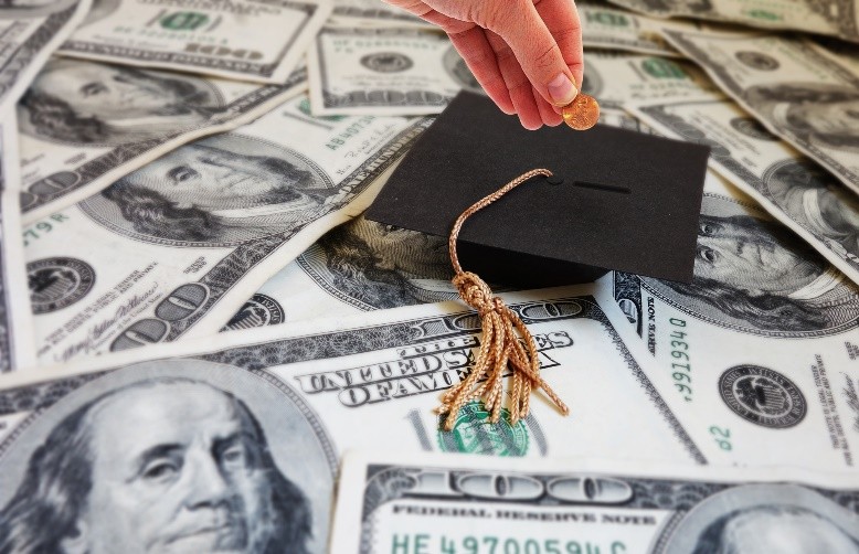 A hand putting a coin into a graduation cap

Description automatically generated