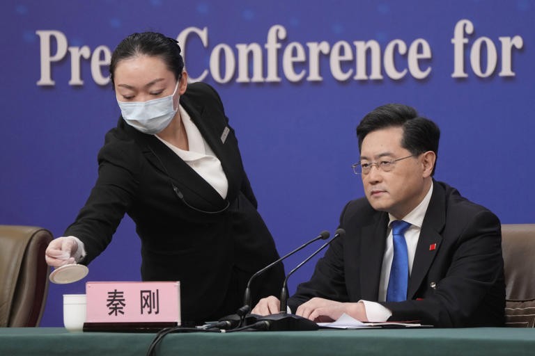 Chinese Foreign Minister Qin Gang looks on as a hostess refills his cup during a press conference held on the sidelines of the annual meeting of China's National People's Congress (NPC) in Beijing, Tuesday, March 7, 2023. (AP Photo/Mark Schiefelbein)