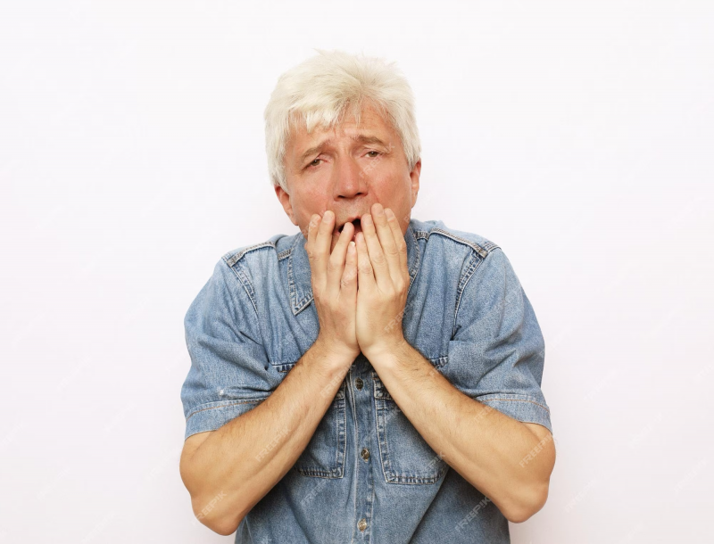 A person with white hair holding his hands to his mouth

Description automatically generated