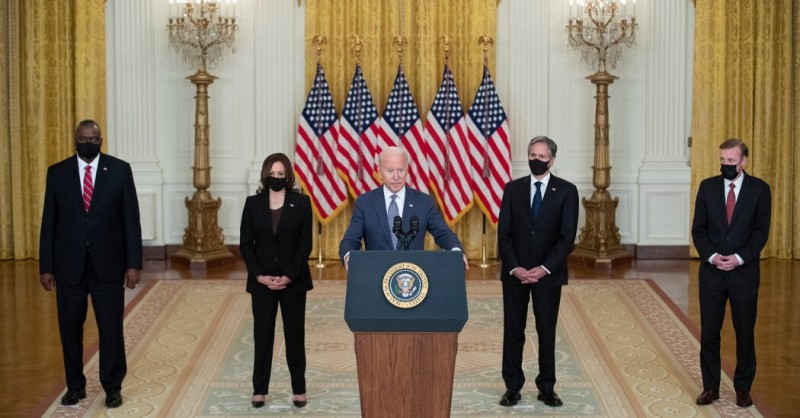 A group of people standing in front of a podium with flags behind them

Description automatically generated with low confidence