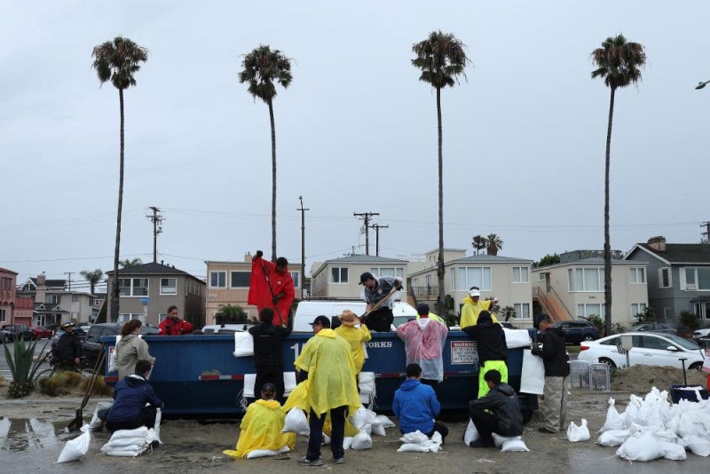 Volunteers and members of the Long Beach fire department fill sandbags at Belmont Shore beach in Long Beach, California, on Sunday.