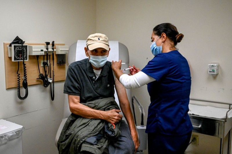 A person in a blue scrubs giving a person a medical test

Description automatically generated