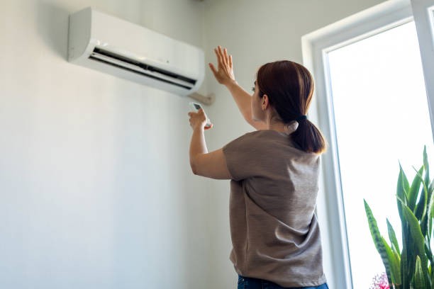 Woman turning on air conditioner Woman turning on air conditioner indoor air conditioner stock pictures, royalty-free photos & images
