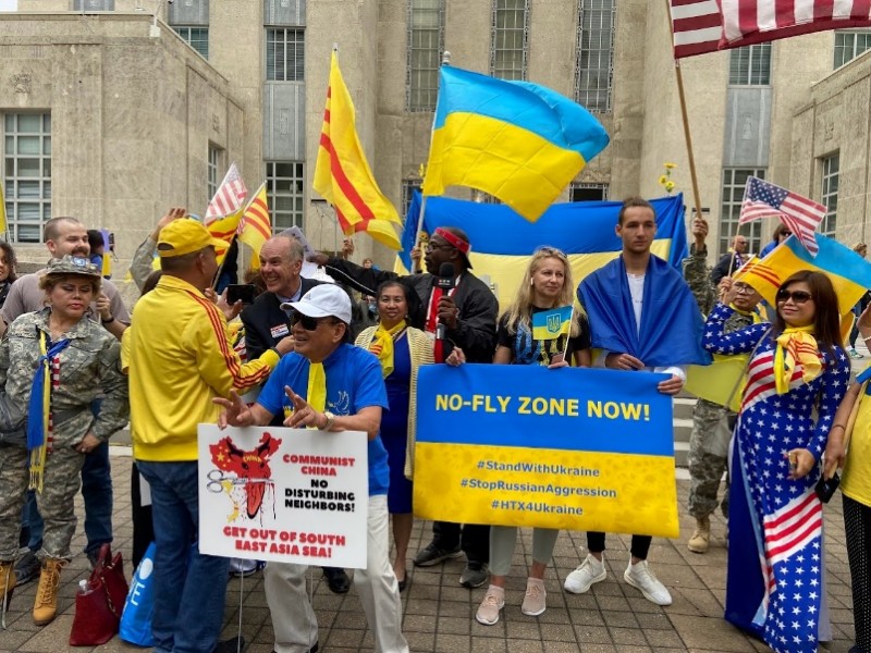 A group of people holding signs and flags

Description automatically generated with medium confidence