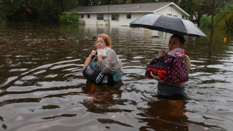 Makatla Ritchter, left, and her mother Keiphra Line wade through floodwater Wednesday in Tarpon Springs, Florida. - Joe Raedle/Getty Images