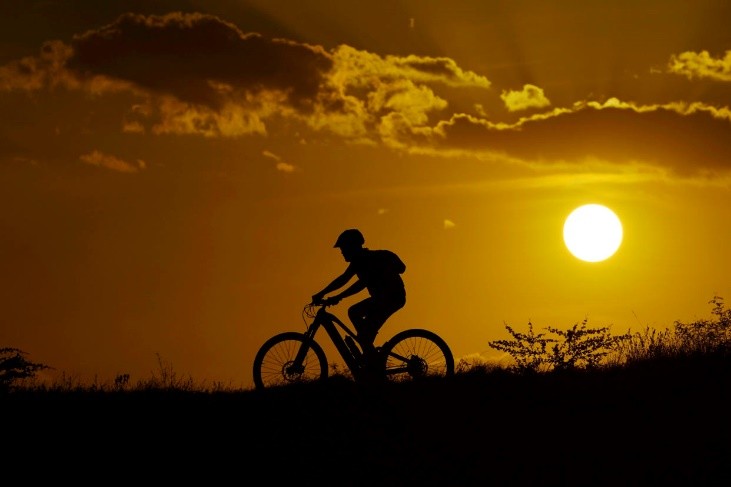 A person riding a bike at sunset

Description automatically generated
